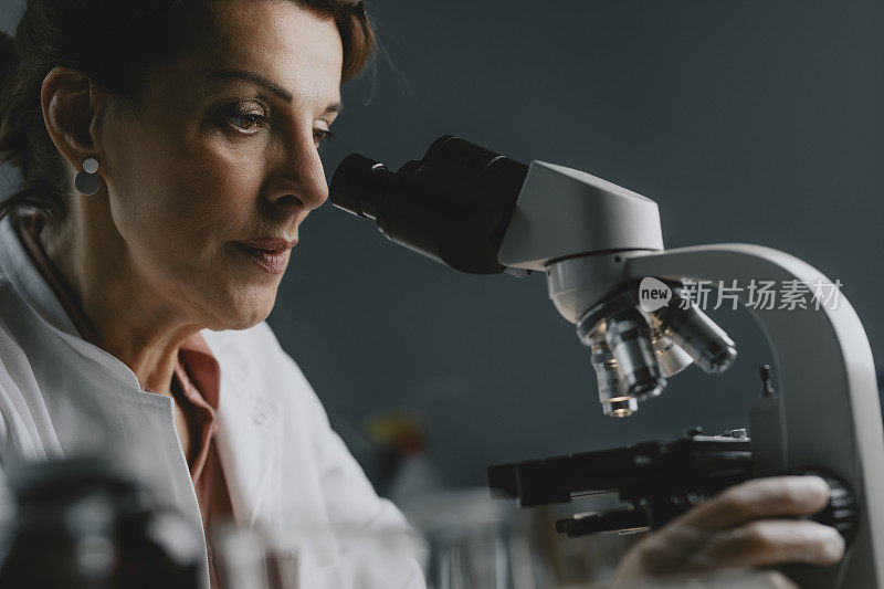 高级女科学家/实验室技术员使用显微镜进行研究